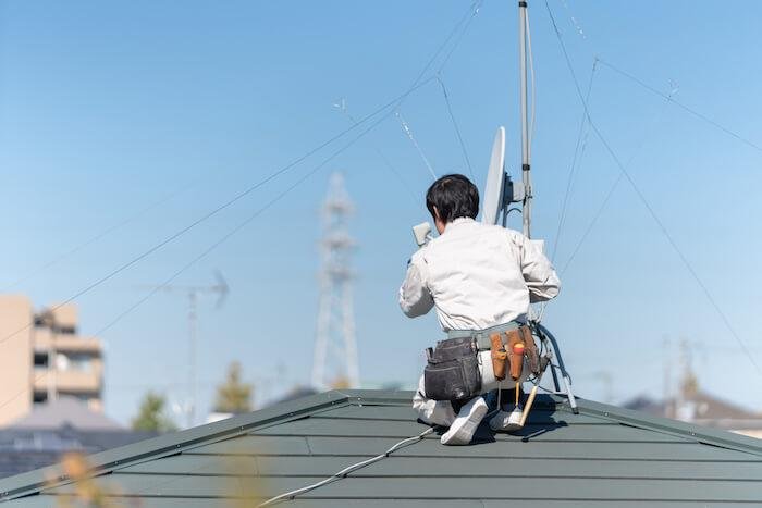 屋根の上でアンテナを設置する工事業者